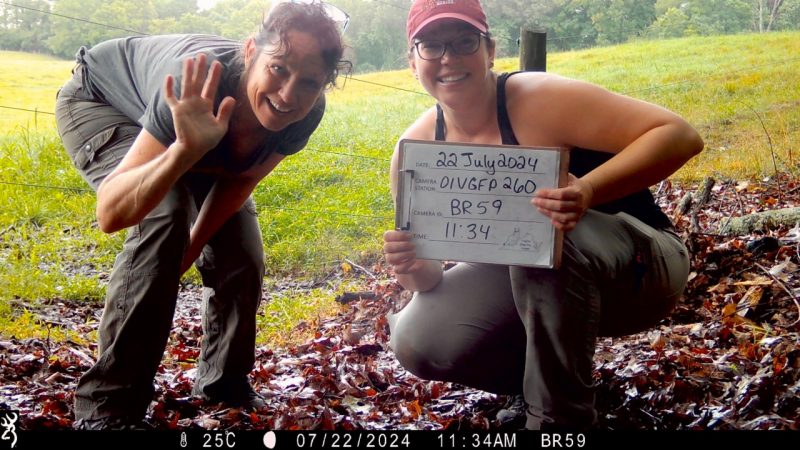 two women in outdoor clothing test a trail camera