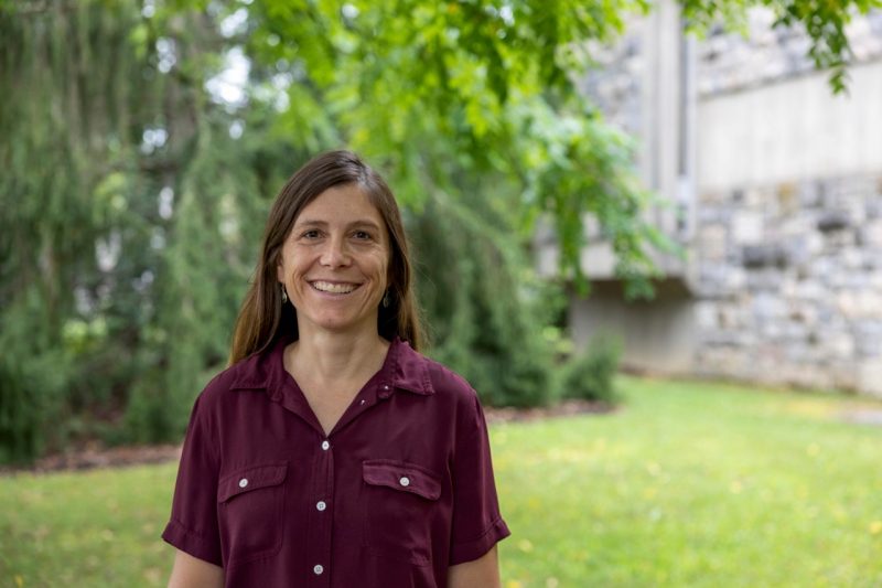 woman with brown hair and maroon shirt in front of trees