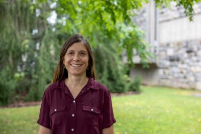woman with brown hair and maroon shirt in front of trees