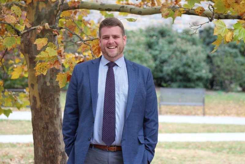 A person stands next to a tree.