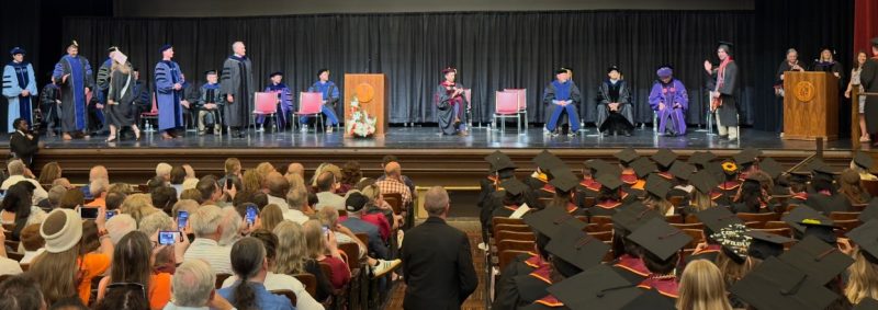 Student, parents, faculty, and staff attend the CNRE commencement in a large auditorium as graduates walk across the stage