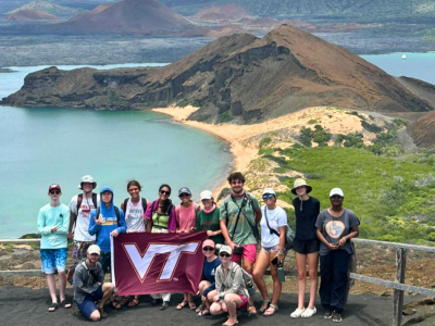 The undergraduate student explorers pose with the flag at a lookout in Bartolomé- Sophia in the Galapagos Islands. Sophia Detrick and Max Nootbar,  feature seventh and eight from left, top row. 